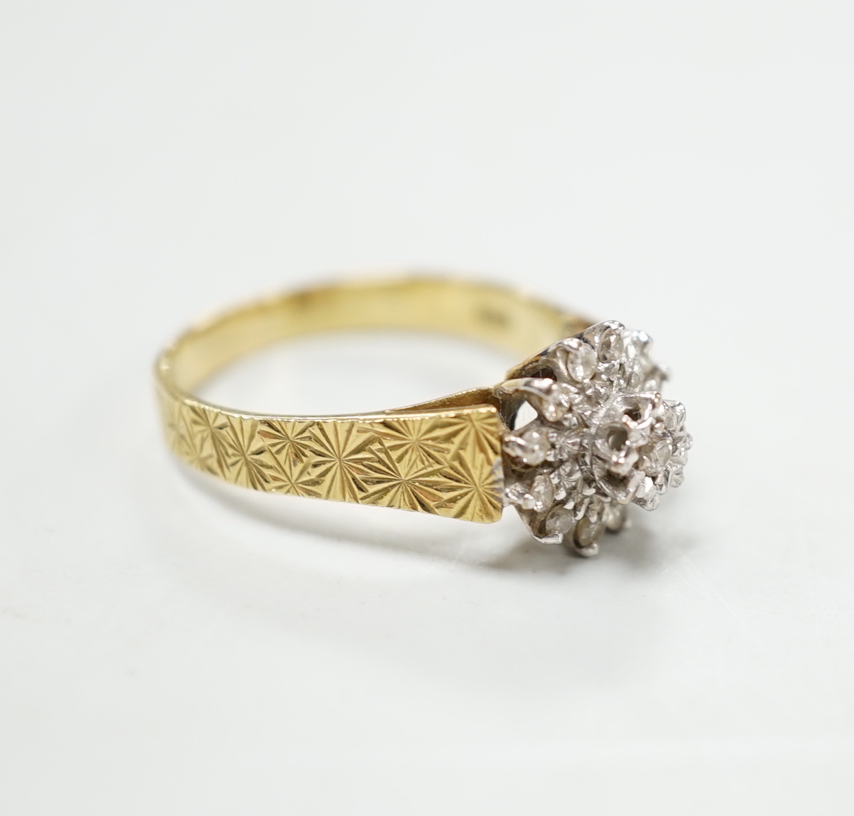 A modern 18ct gold and diamond chip set flower head cluster ring, size P, gross 4.5 grams.